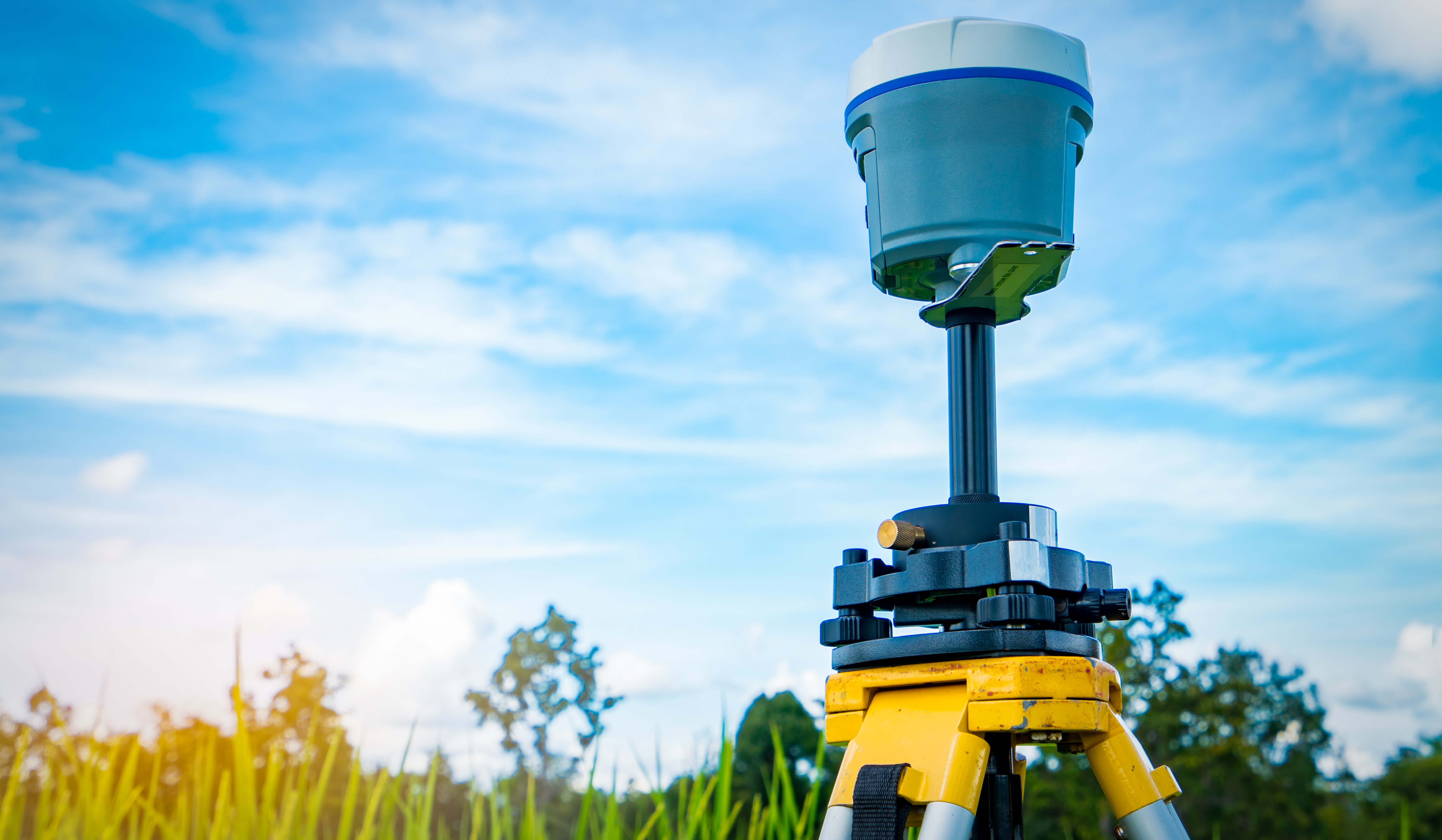 GPS surveying instrument on blue sky and rice field background