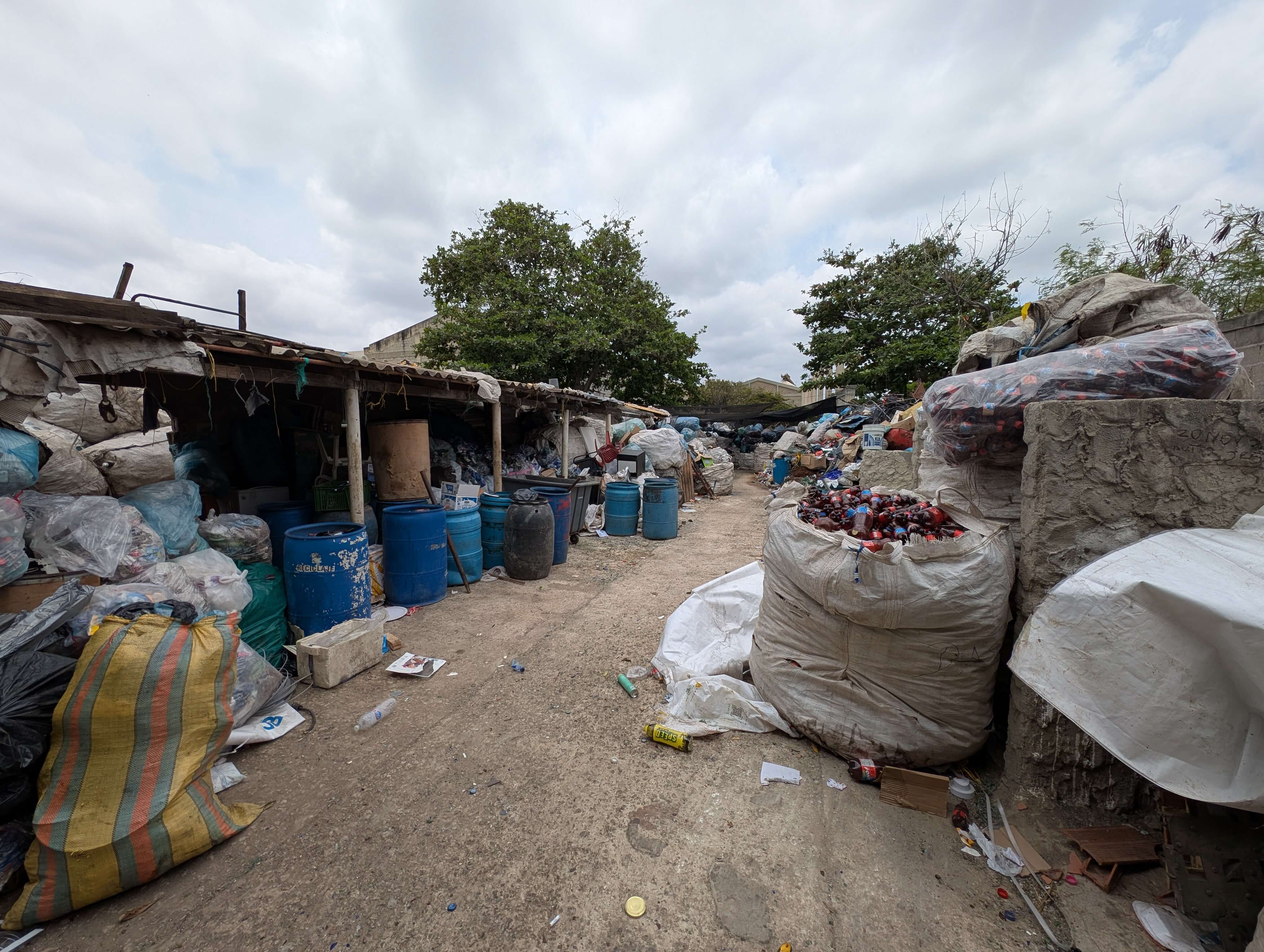A photo of waste collected in piles and bags across a large outdoor site. 