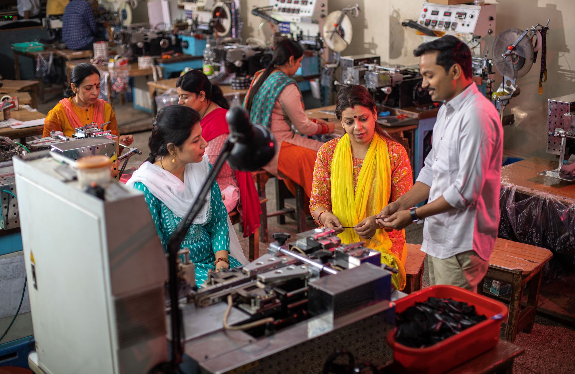 Manager showing sample of printed fabric to female workers at factory