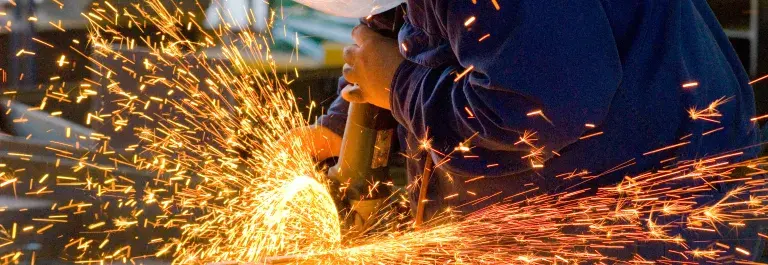 Person in a workshop welding with bright orange sparks flying across © Adobe Stock