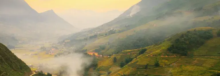 Birds-eye view of mountains and a valley with wispy clouds
