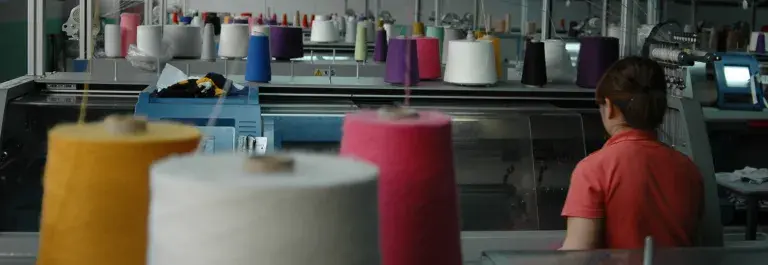 Colourful cotton on sewing machines in the factory with person sitting down © Better Cotton Initiative