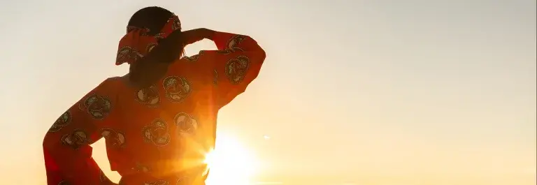 Woman looking out across wheat field in the sunset © Adobe Stock