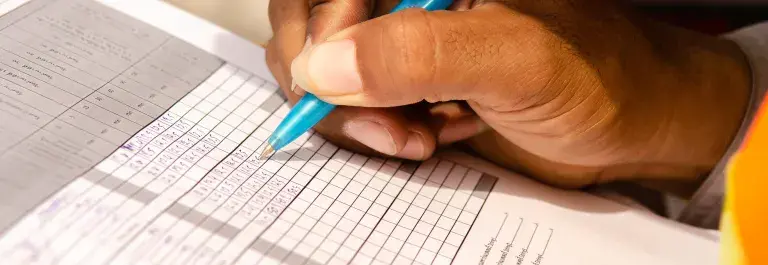 Person checking boxes on a form for an audit © Adobe Stock