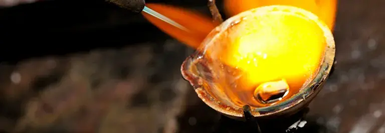 A blowtorch is heating a metal crucible, creating a jet of yellow-orange flame © Adobe Stock