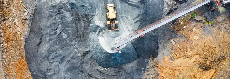 Aerial shot of mine with vehicle driving across black sand © Pexels