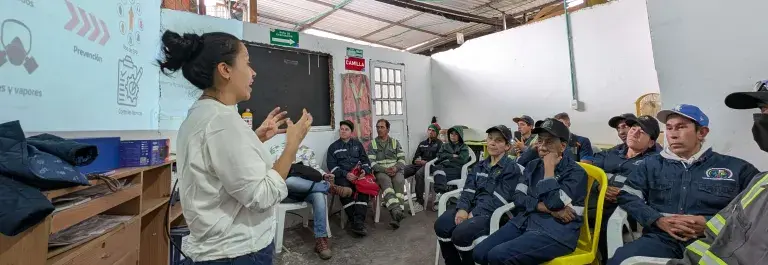Women speaking to group of workers in training session with presentation