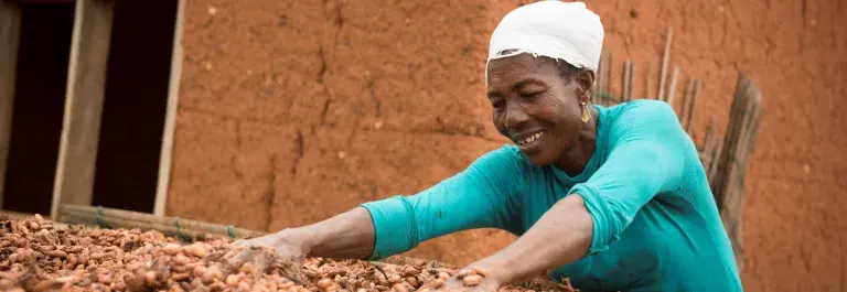 Woman drying out cocoa beans in Ghana © Fairtrade