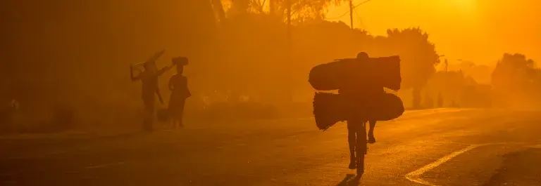 Silhouettes of workers commuting by foot and by bike in the sunset