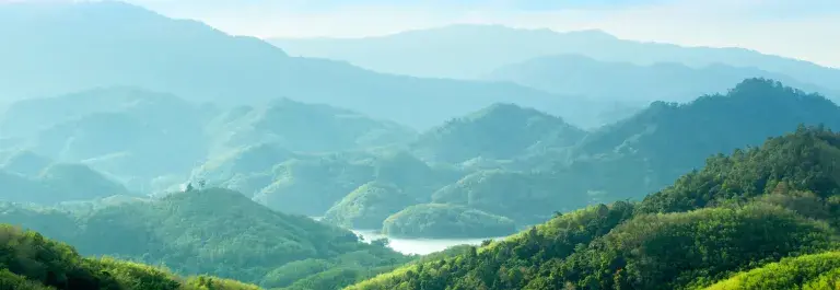 A verdant, mountainous landscape under a blue sky © Adobe Stock