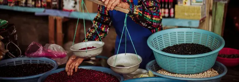 A man weighs beans at his market stall