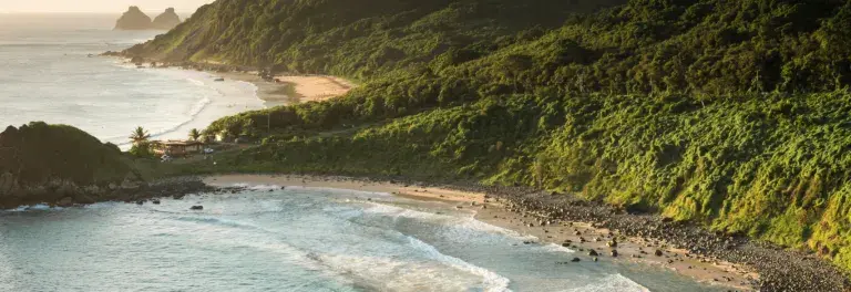 Coastline in Brazil with mountains covered in trees in the sunset