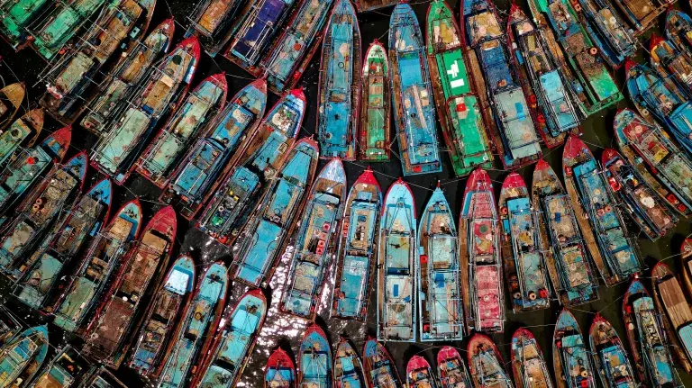 Aerial shot of lots of fishing boats packed up against one another © Pexels