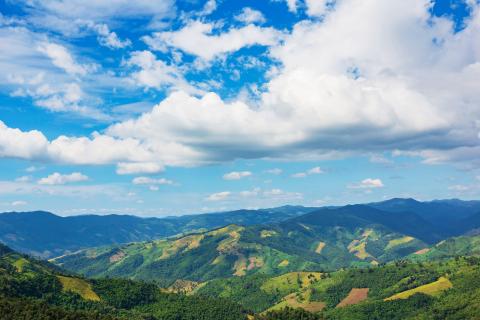 Green hilly landscape view with blue sky