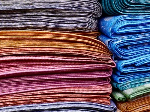 A pile of colourful folded textiles © Pexels