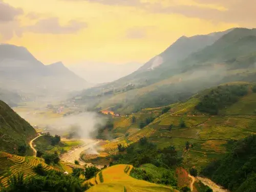 Birds-eye view of mountains and a valley with wispy clouds