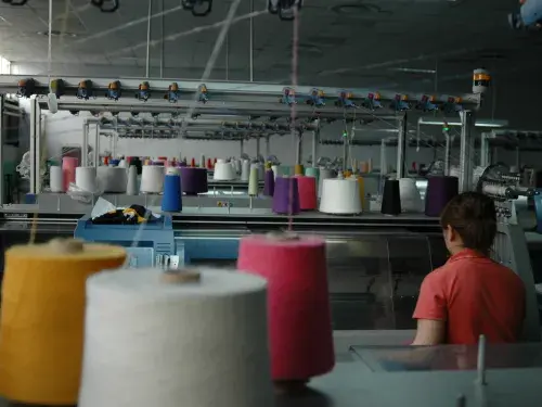 Colourful cotton on sewing machines in the factory with person sitting down © Better Cotton Initiative