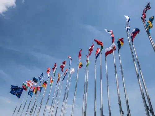 Looking up at flags of different countries against a mostly blue sky © Adobe Stock