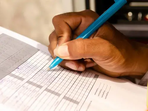 Person checking boxes on a form for an audit © Adobe Stock