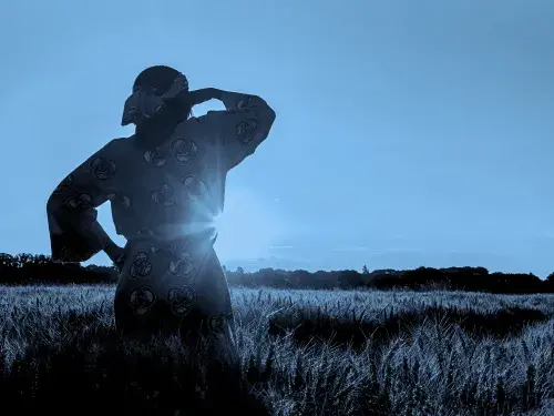 African woman in traditional clothes standing in a field of crops