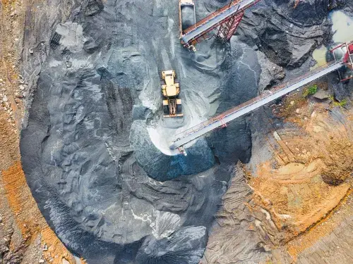 Aerial shot of mine with vehicle driving across black sand © Pexels