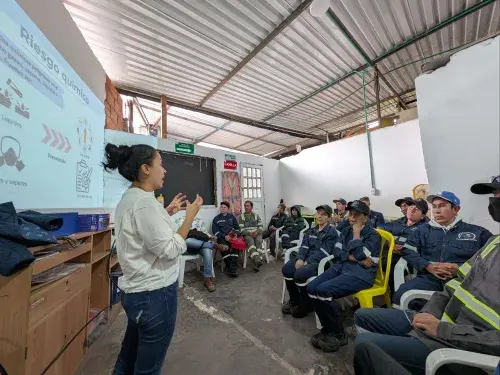 Women speaking to group of workers in training session with presentation