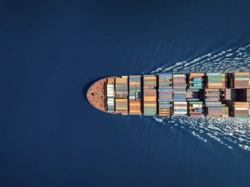 Birds eye view of a shipping container ship on the water, going right to left across the shot
