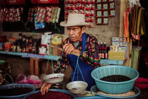 A man weighs beans at his market stall