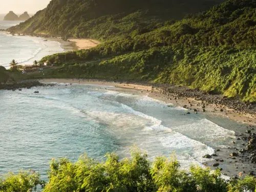 Coastline in Brazil with mountains covered in trees in the sunset