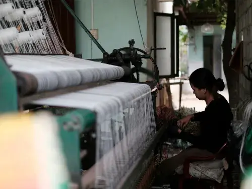 Woman textile worker sitting by weaving equipment with white yarn © Unsplash