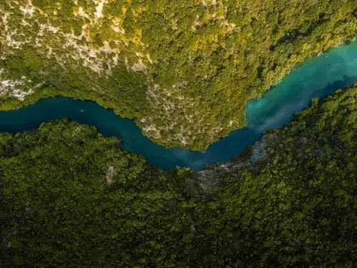 Aerial shot of a blue winding river through green and rocky landscape