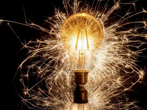 Light bulb against a dark background with light beams scattered around