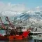 Snowy mountains in the background of a harbour with a red fishing boat © Pexels