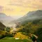 Birds-eye view of mountains and a valley with wispy clouds