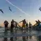 Group of people fishing with a large net on a beach with birds flying above them against a sunset sky © Unsplash