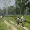 People with large baskets walking down dirt track in fields © Fair Trade