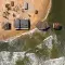 Aerial view of houses on a coastline with two on stilts in the water