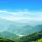 A verdant, mountainous landscape under a blue sky © Adobe Stock