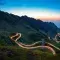 Mountain landscape with brightly lit winding road at dusk © Adobe Stock
