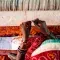 Textile worker weaving threads surrounded by red fabric © GoodWeave