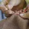 Person sewing fabric with orange thread and needle © Adobe Stock