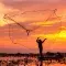 Fisherman net being cast with an orange and yellow sunset sky © Adobe Stock