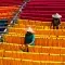 Two people hanging coloured yarns and textiles in the sun
