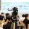 Video camera filming a conference with a projected screen and people in the background © Pexels